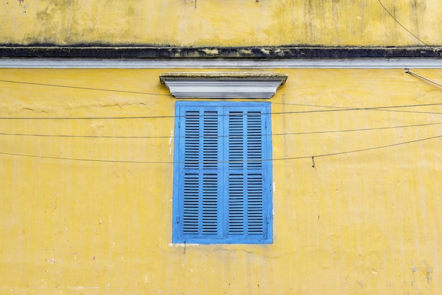 Ventana azul en la pared amarilla en Hoi An