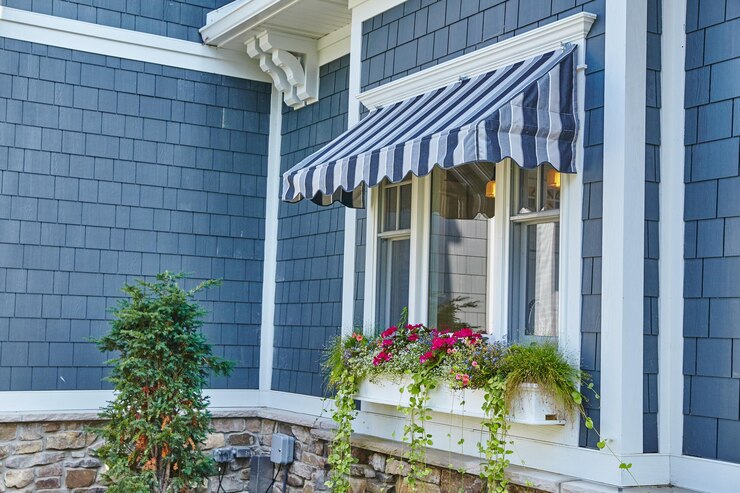 Ventana de una casa acogedora con toldo azul y caja de flores