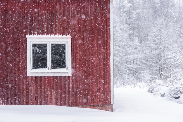 La ventana de la casa en el bosque se ha cubierto de nieve pesada y cielo malo en la temporada de invierno en Tuupovaara, Finlandia.