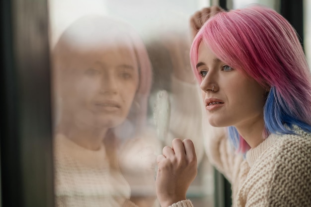 En la ventana Cerca de una chica con cabello rosado cerca de la ventana