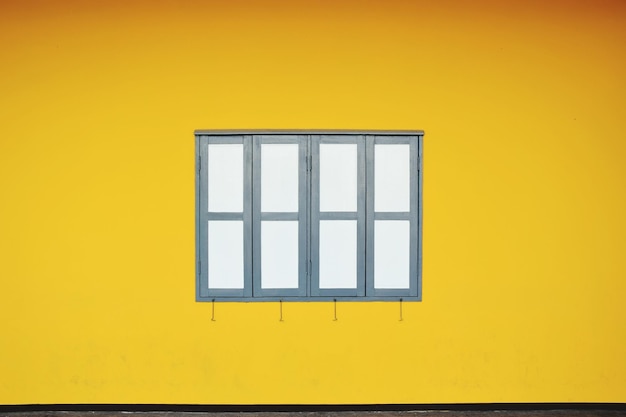 Ventana cerrada en medio de una pared amarilla