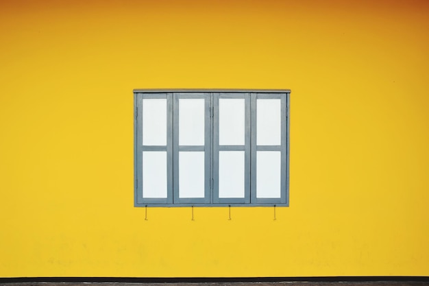 Foto ventana cerrada en medio de una pared amarilla