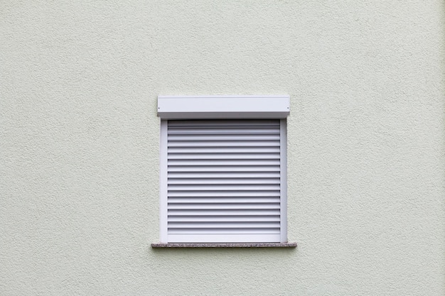 Foto ventana cerrada con una persiana en una pared blanca