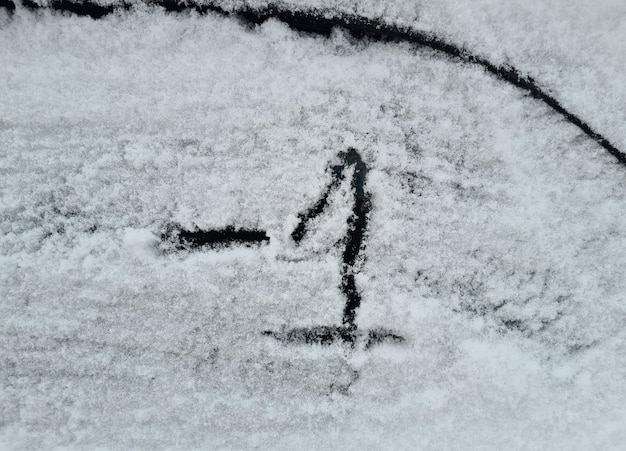 Ventana de coche congelada con texto 1 rayado en hielo