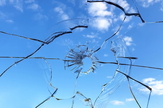 Ventana de cristal rota sobre fondo de cielo azul