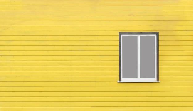 Ventana gris en la pared de madera amarilla