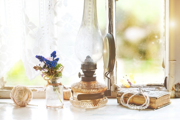 Ventana interior con lámpara vintage y flores silvestres.