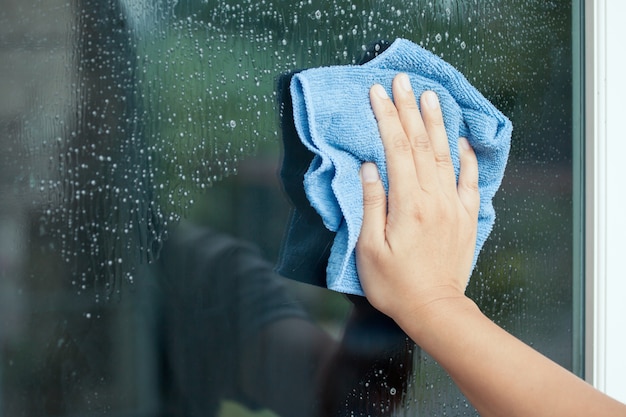 Ventana de limpieza de mano de mujer con trapo