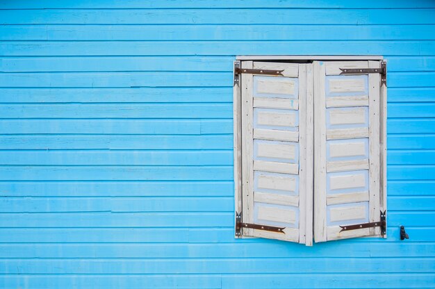 Ventana de madera blanca en la pared azul