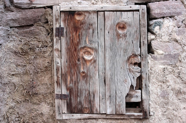 Ventana de madera cerrada en casa de piedra