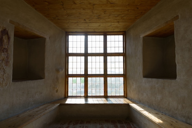 Ventana de madera cerrada con dos orificios cuadrados uno frente al otro cementado a bordo en el piso y el techo con luz solar entrando