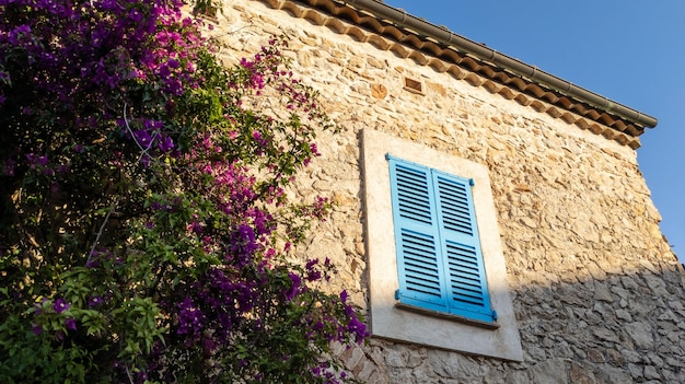 ventana de madera de Provenza persiana azul en la fachada de la casa de piedra en Francia