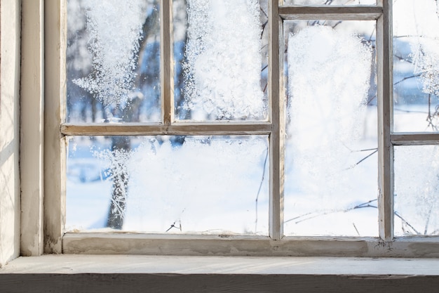 Ventana de madera vieja con escarcha de invierno