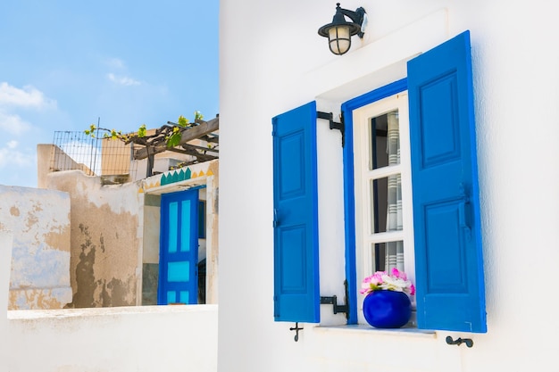 Ventana con persianas azules y flores Arquitectura blanca en la isla de Santorini Grecia
