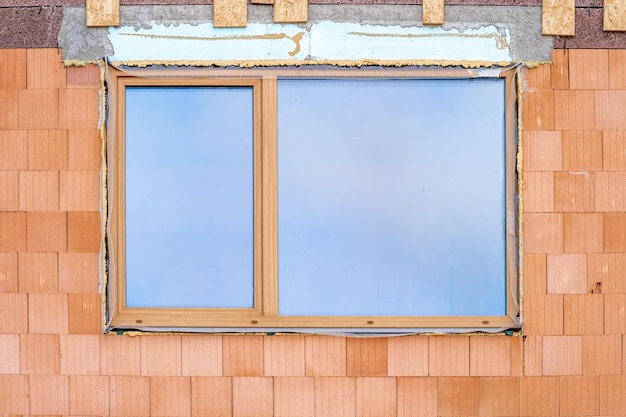 Ventana de plástico en una pared de ladrillos en la construcción de una casa