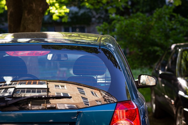 Ventana trasera del coche azul aparcado en la calle en un día soleado de verano, vista trasera. Maqueta para calcomanías o calcomanías