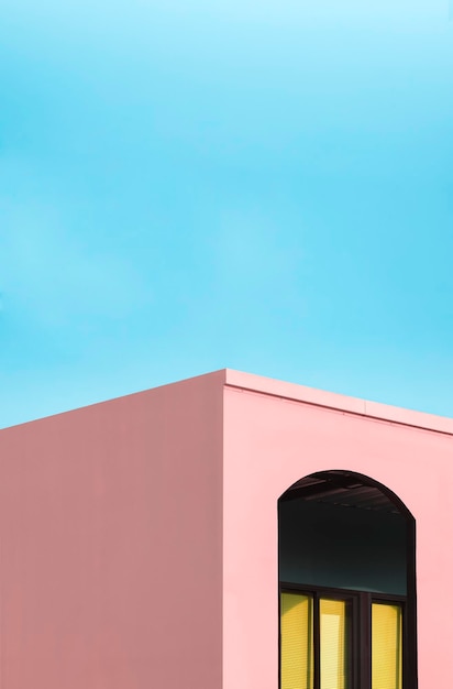 Foto ventana de vidrio dentro de la pared del arco de la casa moderna rosa contra el fondo del cielo azul en tonos pastel