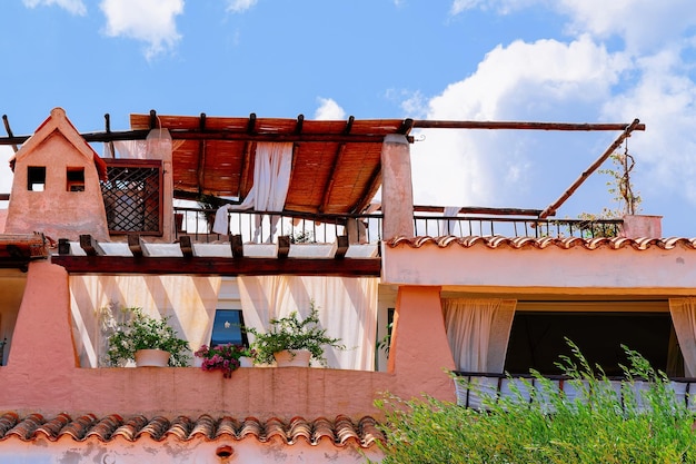 Ventanas y balcones con flores de complejo residencial. Edificio de apartamentos. Arquitectura casera costera en la ciudad turística de lujo de Porto Cervo en la isla de Cerdeña en Italia en verano.