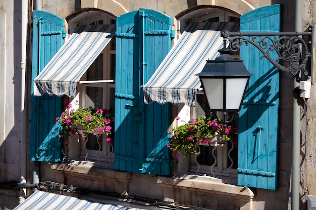 Ventanas de la casa del estilo de Francia Provence, obturadores azules y rectángulos de la flor.