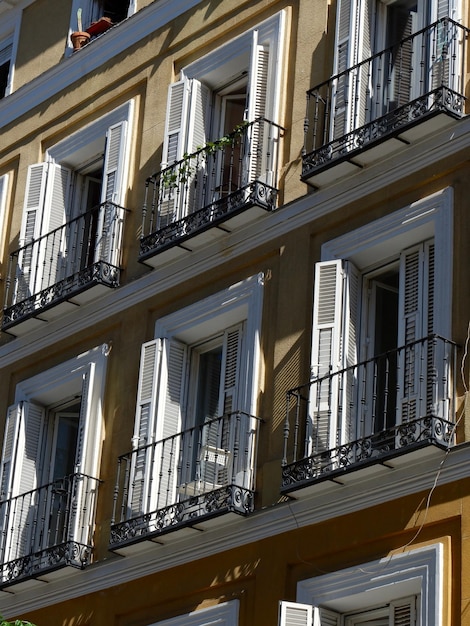 Ventanas clásicas con persianas de color blanco en la fachada vintage exterior en el barrio de Malasaña de Madrid España Foto vertical