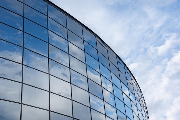 Las ventanas espejadas de un edificio moderno reflejan el cielo azul y las nubes