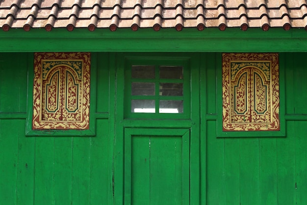 Las ventanas de madera talladas balinesas en la pared verde