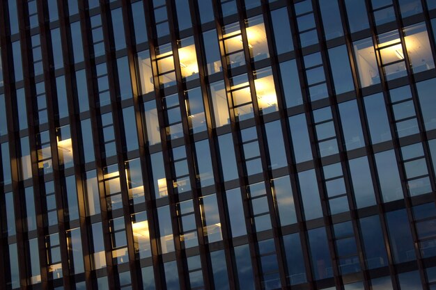 Ventanas vacías iluminadas del edificio de oficinas por la tarde.