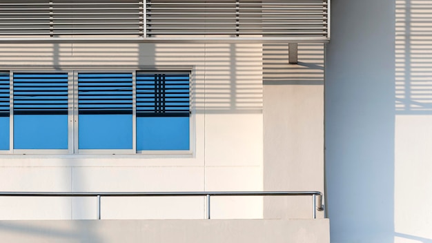 ventanas de vidrio azul con toldo de acero inoxidable en el balcón de un edificio de oficinas blanco y moderno