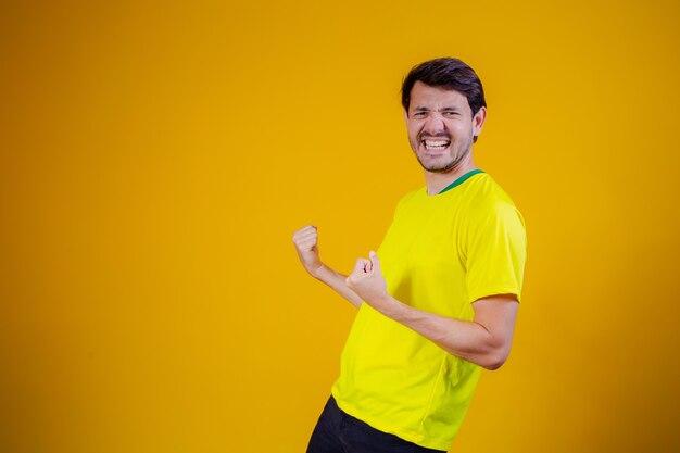 Ventilador brasileño celebrando sobre fondo amarillo. ¡Sí!