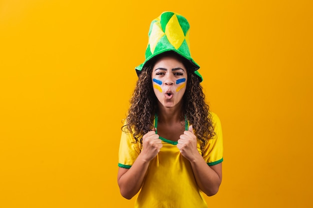 Ventilador brasileño. Ventilador brasileño celebrando el fútbol o el partido de fútbol sobre fondo amarillo. Colores de Brasil.