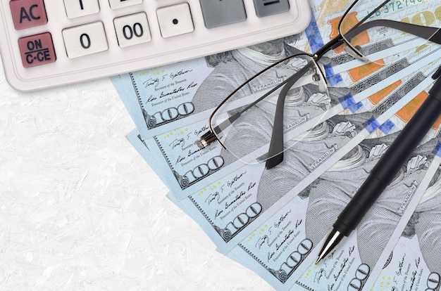 Ventilador de notas de 100 dólares e calculadora com óculos e caneta. Empréstimo empresarial ou conceito de temporada de pagamento de impostos. Planejamento financeiro