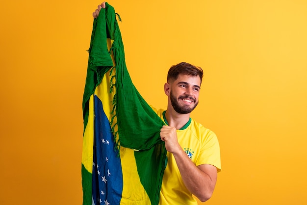 Ventilador do homem segurando um fundo amarelo da bandeira brasileira. Cores do Brasil em fundo, verde, azul e amarelo. Eleições, futebol ou política.