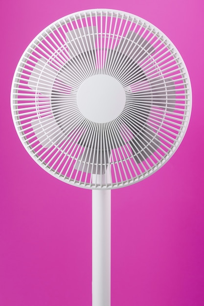 Ventilador eléctrico en color blanco con un diseño moderno para enfriar la habitación sobre un fondo rosa.