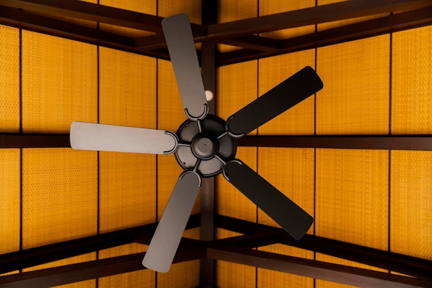 Ventilador de techo interior marrón sobre una viga de soporte de madera expuesta con un techo de madera decorado en el vestíbulo de la sala de estar de una casa contemporánea concepto de diseño de interiores