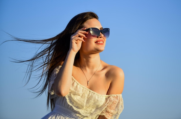 Vento de mudança Liberdade e harmonia Psicologia feminina Mulher bonita no céu azul de dia ensolarado Moda de verão Garota em óculos de sol cópia espaço Modelo chique em terno de verão vestido Em direção ao verão