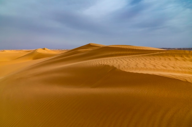 Vento forte ao pôr do sol sobre as dunas de areia no deserto Tempestade de areia no deserto do Saara