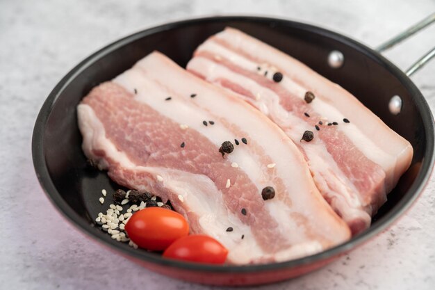 Ventre de cerdo en una sartén con semillas de pimienta tomates y especias