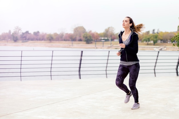 Ver en activo joven bella mujer corriendo por el río