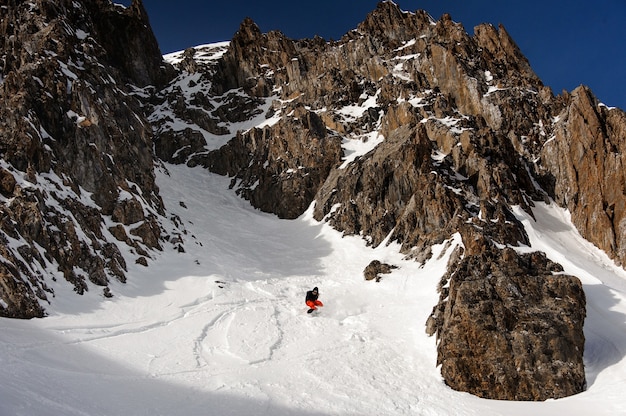 Ver al snowboarder masculino en casco deslizándose por la ladera de la montaña