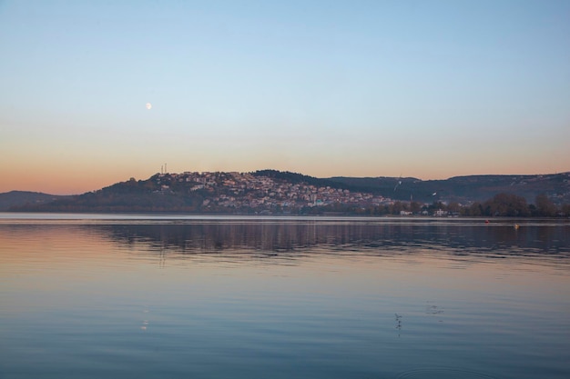 Ver casas à beira do lago, cidade. vista para o lago por do sol. céu laranja e lua. Lago Sapanca à noite.