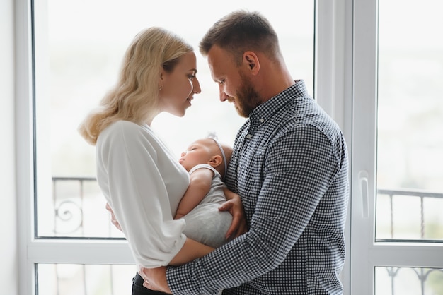 Ver en familia feliz con bebé recién nacido junto a la ventana