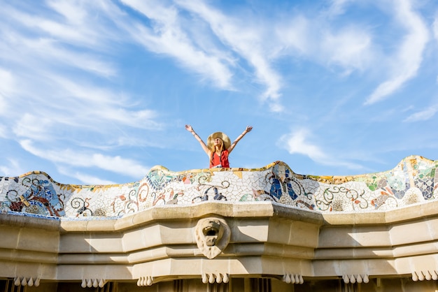 Foto ver en la hermosa terraza decorada con mosaico con turista mujer feliz en el parque güell de barcelona. vista de gran angular con espacio de copia