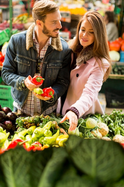 Ver no jovem casal comprando legumes em um mercado