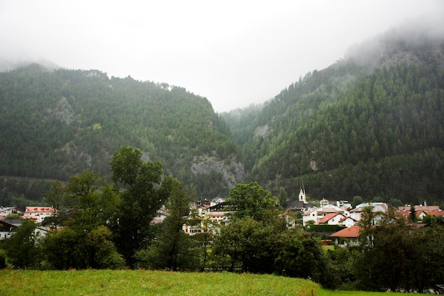 Ver el paisaje urbano y el paisaje de la ciudad de Pfunds con la iglesia de Lourdeskapelle en la mañana y lloviendo en el Tirol Austria
