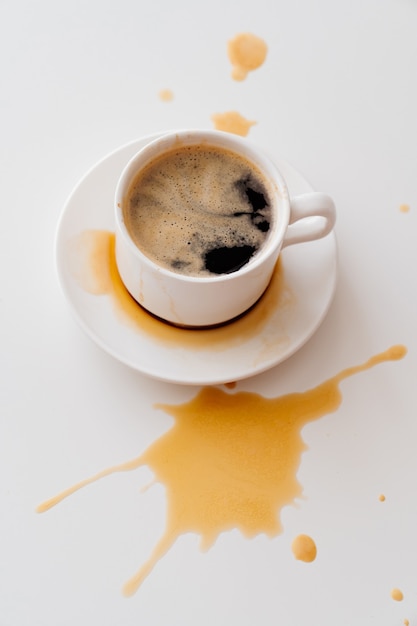 Ver la parte superior. de la taza de café se esparcen salpicaduras sobre la mesa blanca. desayuno tradicional de la mañana. vivacidad en los ascensos de la madrugada. capuchino