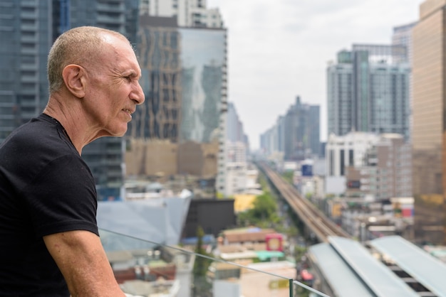 Ver perfil de calvo turista senior hombre mirando la vista de la ciudad