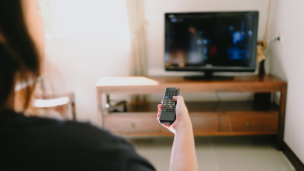 Ver televisión inteligente y usar el control remoto tv Mano sujetando el control remoto de audio de la televisión