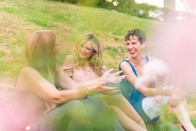 Ver a través de algunas hojas de mujeres maduras sentadas en el parque charlando. Hermosas mujeres maduras pasando un buen rato juntas en el parque.