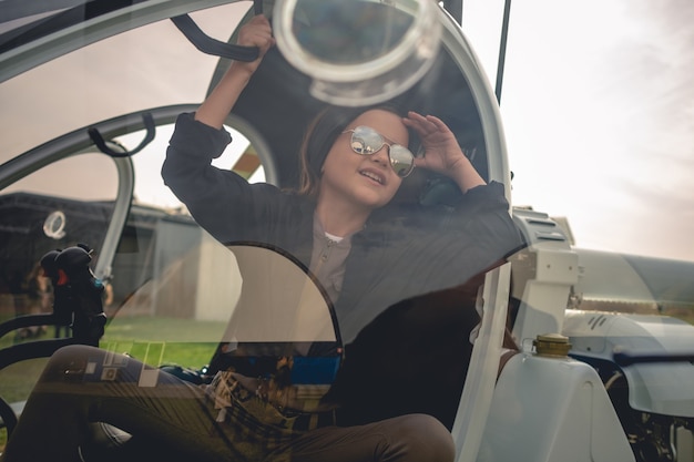 Foto ver a través del vidrio de la cabina de un helicóptero de una alegre niña interpolación mirando al cielo