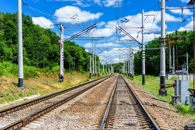 Ver en una vía de ferrocarril y nubes blancas en un cielo azul